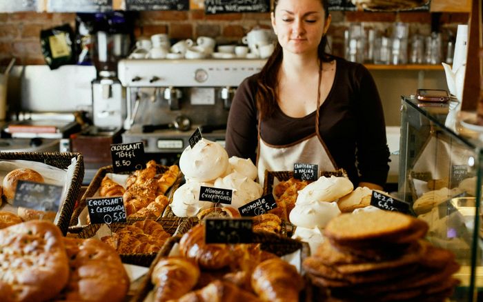 A bakery owner behind a counter full of fresh bread