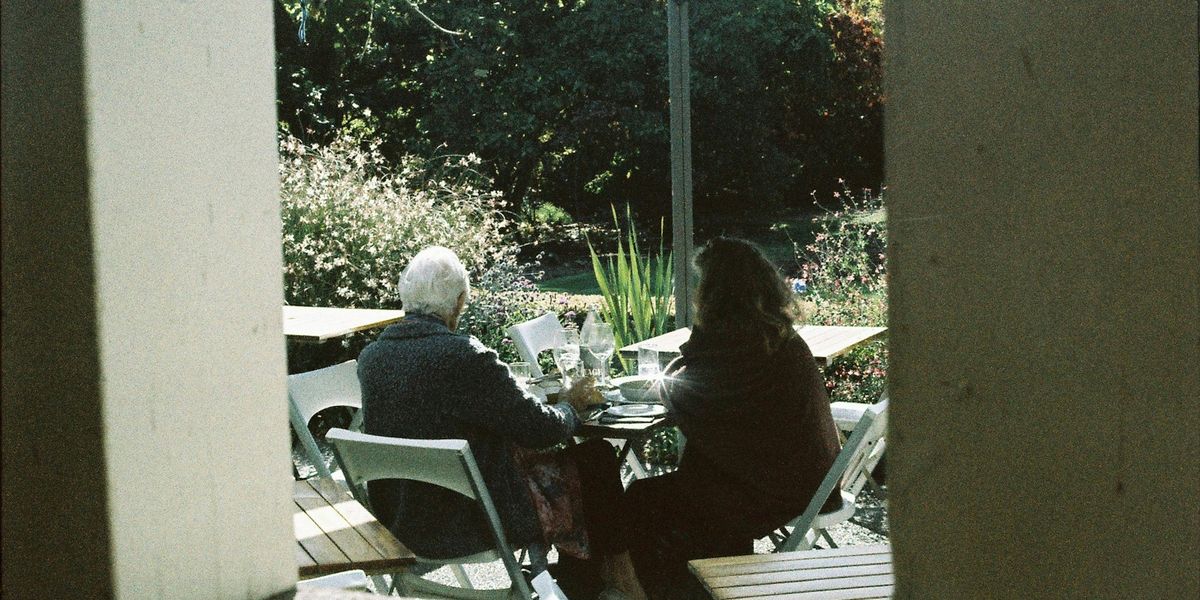 People sitting at an outdoor cafe table under an umbrella in Christchurch