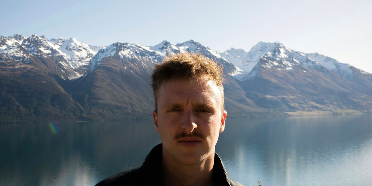 A man standing in front of a New Zealand lake and mountains