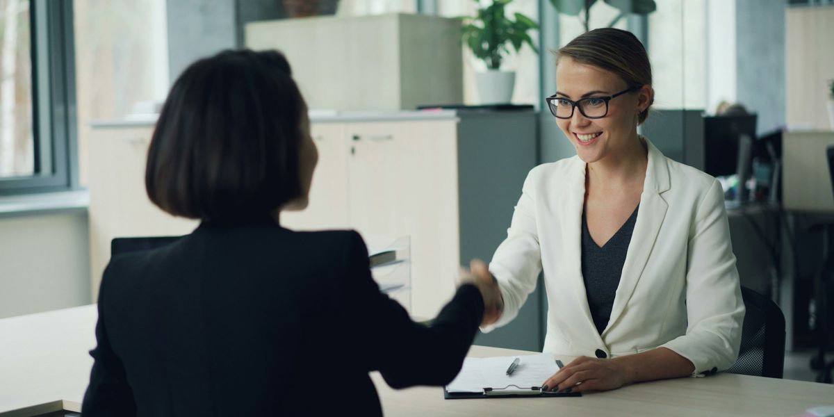Two business owners shaking hands across a desk