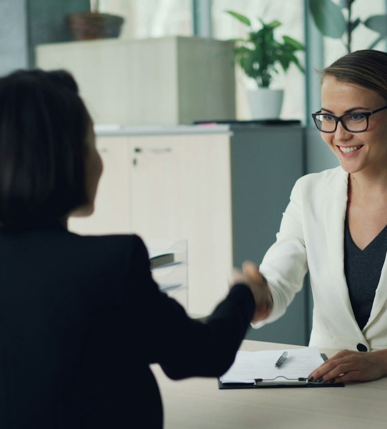 Two business owners shaking hands across a desk