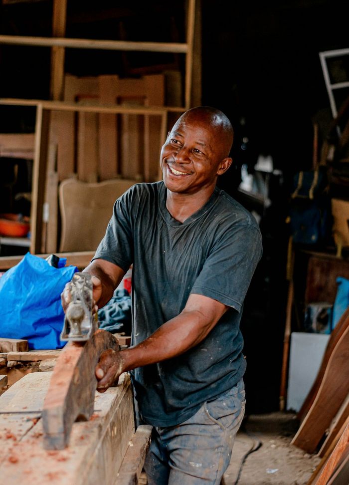 A joiner smiling as he works on a piece of timber in his workshop