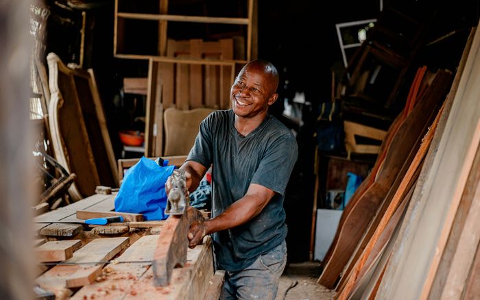 A joiner smiling as he works on a piece of timber in his workshop