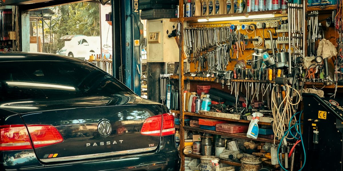 A mechanic workshop with tools lining the walls and a car ready for service