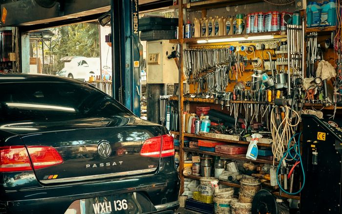 A mechanic workshop with tools lining the walls and a car ready for service