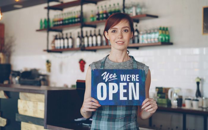 A smiling small business owner welcoming customers to her shop
